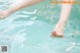 A person's feet in the water of a swimming pool.