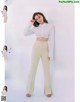 A woman in a white shirt and beige pants posing for a magazine.