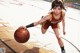 A woman in a basketball uniform dribbling a basketball on a court.