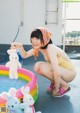 A woman in a yellow bathing suit playing with stuffed animals.