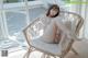 A woman in a bikini sitting on a wicker chair.