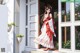 A woman in a red and white dress standing in front of a door.