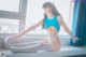 A woman in a blue leotard sitting on a window sill.