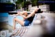 A woman sitting on a bench next to a pool.