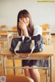 A woman sitting at a desk with a bag on her lap.