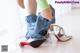 A woman is putting on a pair of silver shoes.