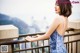 A woman in a blue dress standing on a balcony.